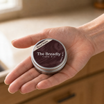The wood balm tin held in hand, showing its size